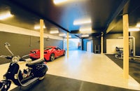 a garage with a red scooter and a car